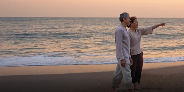 A couple walking on the beach at sunset pointing to something out of frame