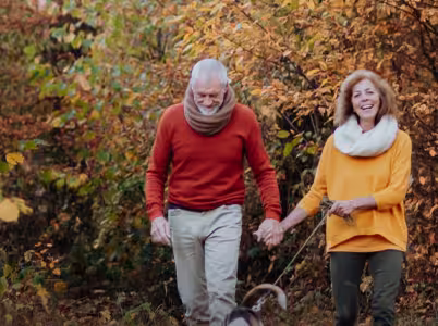 A couple walking their dog in the woods